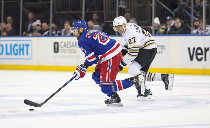 Nov 25, 2023; New York, New York, USA; New York Rangers center Barclay Goodrow (21) moves the puck up ice past Boston Bruins defenseman Hampus Lindholm (27) during the third period at Madison Square Garden. Mandatory Credit: Danny Wild-USA TODAY Sports