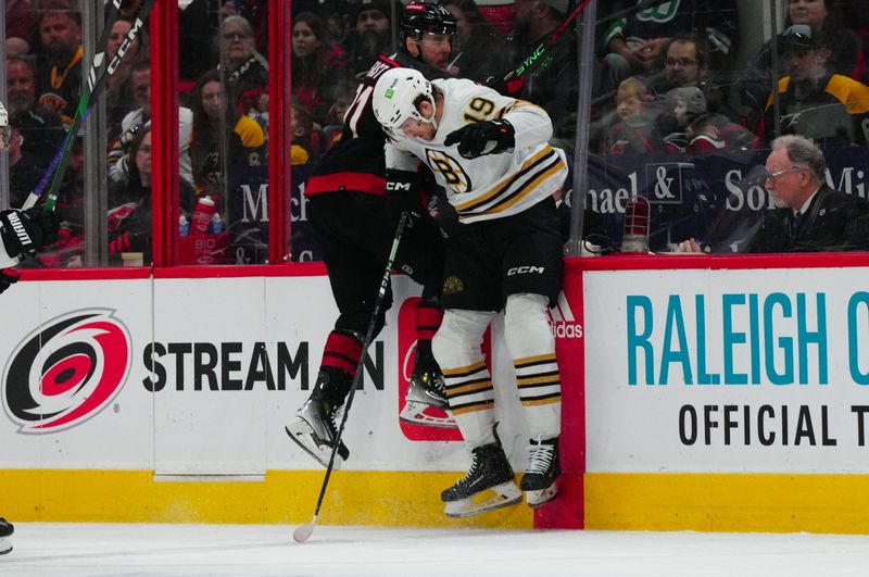 Apr 4, 2024; Raleigh, North Carolina, USA; Boston Bruins center Johnny Beecher (19) checks Carolina Hurricanes right wing Jesper Fast (71) during the first period at PNC Arena. Mandatory Credit: James Guillory-USA TODAY Sports