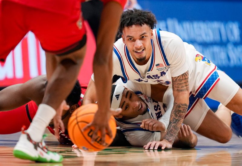 Dec 14, 2024; Lawrence, Kansas, USA; Kansas Jayhawks guard Zeke Mayo (5) and guard Dajuan Harris Jr. (3) dive for a loose ball during the second half against the North Caroline State Wolfpack at Allen Fieldhouse. Mandatory Credit: Jay Biggerstaff-Imagn Images