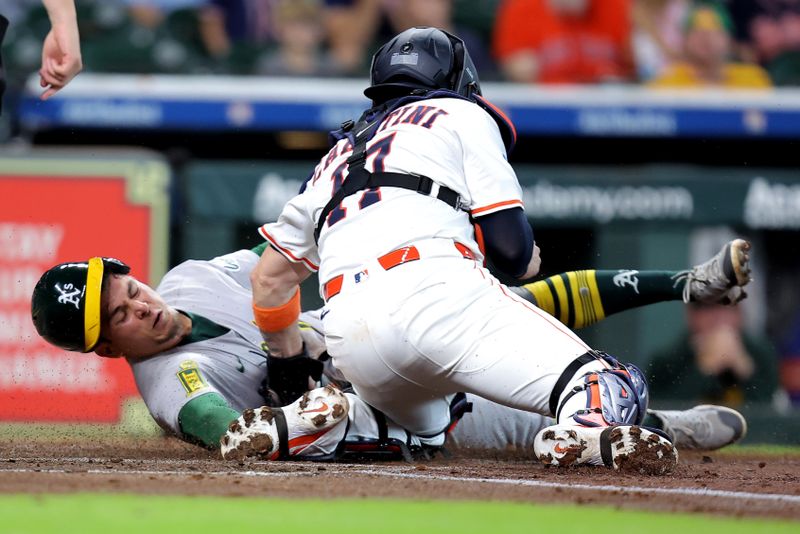May 28, 2025; Houston, Texas, USA; Athletics second baseman Luis Urias (17) sides into home plate to score a run while beating the tag by Houston Astros catcher Victor Caratini (17) during the third inning at Daikin Park. Mandatory Credit: Erik Williams-Imagn Images