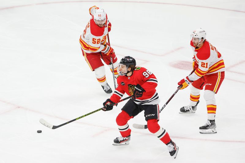 Mar 26, 2024; Chicago, Illinois, USA; Chicago Blackhawks center Connor Bedard (98) looks to pass the puck against the Calgary Flames during the first period at United Center. Mandatory Credit: Kamil Krzaczynski-USA TODAY Sports