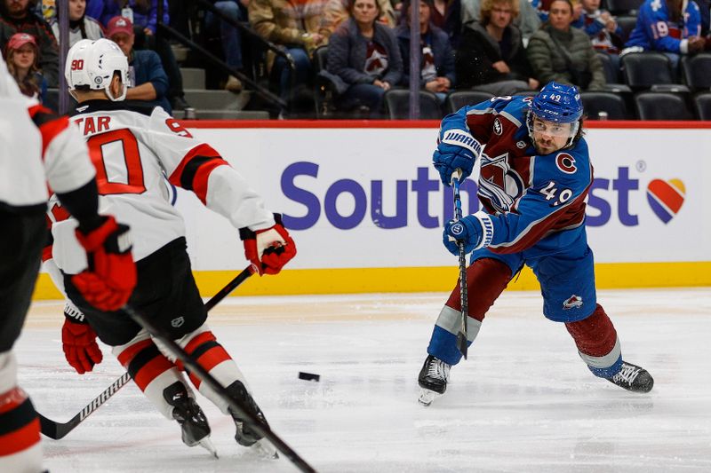Feb 26, 2025; Denver, Colorado, USA; Colorado Avalanche defenseman Samuel Girard (49) attempts a shot as New Jersey Devils left wing Tomas Tatar (90) defends in the second period at Ball Arena. Mandatory Credit: Isaiah J. Downing-Imagn Images