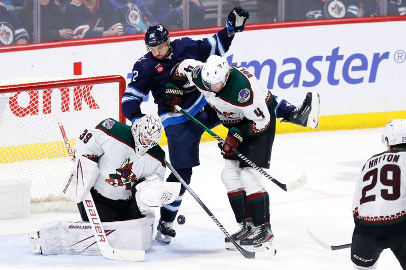 Feb 25, 2024; Winnipeg, Manitoba, CAN; Arizona Coyotes defenseman Juuso Valimaki (4) ties up Winnipeg Jets right wing Nino Niederreiter (62) as Arizona Coyotes goaltender Connor Ingram (39) misses a glove save in the third period at Canada Life Centre. Mandatory Credit: James Carey Lauder-USA TODAY Sports