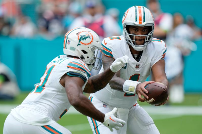 Miami Dolphins quarterback Tua Tagovailoa (1) hands off the ball to Miami Dolphins running back Raheem Mostert (31) during the second half of an NFL football game against the New England Patriots, Sunday, Oct. 29, 2023, in Miami Gardens, Fla. (AP Photo/Wilfredo Lee)