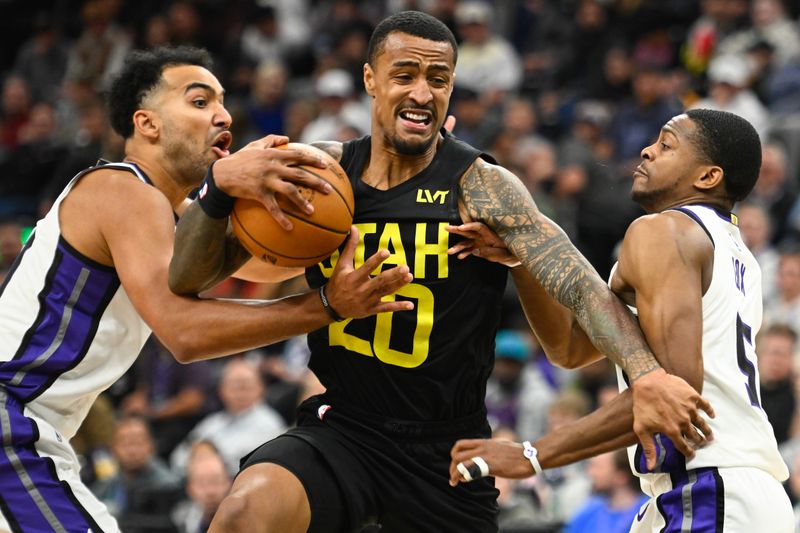 SALT LAKE CITY, UTAH - OCTOBER 29: John Collins #20 of the Utah Jazz drives between Trey Lyles #41 and De'Aaron Fox #5 of the Sacramento Kings during the second half of a game at Delta Center on October 29, 2024 in Salt Lake City, Utah. NOTE TO USER: User expressly acknowledges and agrees that, by downloading and or using this photograph, User is consenting to the terms and conditions of the Getty Images License Agreement.  (Photo by Alex Goodlett/Getty Images)