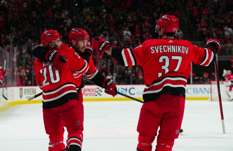 Jan 13, 2024; Raleigh, North Carolina, USA;  Carolina Hurricanes defenseman Brett Pesce (22) is congratulated by center Sebastian Aho (20) right wing Andrei Svechnikov (37) after his goal against the Pittsburgh Penguins during the first period at PNC Arena. Mandatory Credit: James Guillory-USA TODAY Sports