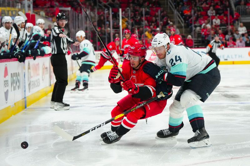 Oct 26, 2023; Raleigh, North Carolina, USA; Seattle Kraken defenseman Jamie Oleksiak (24) goes to check Carolina Hurricanes center Seth Jarvis (24) in the third period at PNC Arena. Mandatory Credit: James Guillory-USA TODAY Sports