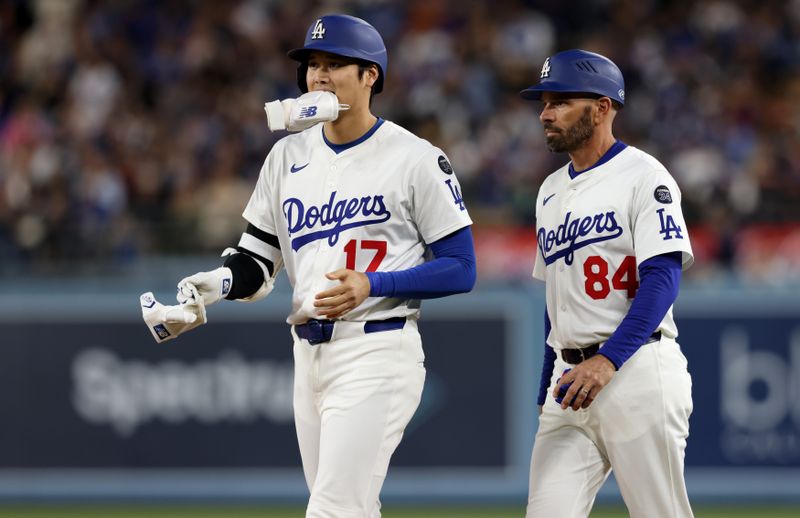 May 14, 2025; Los Angeles, California, USA; Los Angeles Dodgers designated hitter Shohei Ohtani (17) celebrates with first base coach Chris Woodward (84) after an infield single during the sixth inning against the Athletics at Dodger Stadium. Mandatory Credit: Jason Parkhurst-Imagn Images