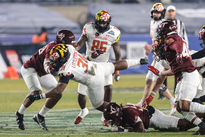 Dec 29, 2021; New York, NY, USA; Maryland Terrapins running back Antwaine Littleton II (31) is tackled by Virginia Tech Hokies safety Tae Daley (17) and defensive back DJ Harvey (20) during the second half of the 2021 Pinstripe Bowl at Yankee Stadium. Mandatory Credit: Vincent Carchietta-USA TODAY Sports