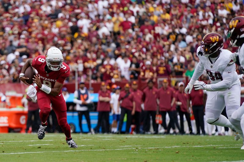 Arizona Cardinals quarterback Joshua Dobbs (9) runs with the ball as Washington Commanders defensive tackle Daron Payne (94) moves in at right during the first half of an NFL preseason football game, Sunday, Sept. 10, 2023, in Landover, Md. (AP Photo/Alex Brandon)