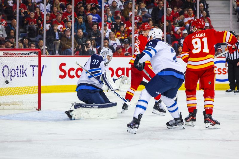 Feb 19, 2024; Calgary, Alberta, CAN; Calgary Flames center Nazem Kadri (91) scores a goal against Winnipeg Jets goaltender Connor Hellebuyck (37) during the second period at Scotiabank Saddledome. Mandatory Credit: Sergei Belski-USA TODAY Sports