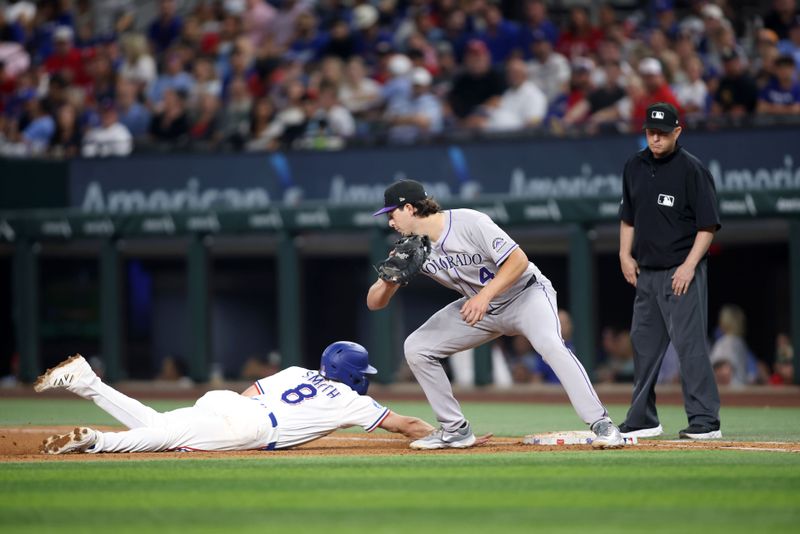 May 14, 2025; Arlington, Texas, USA; Texas Rangers shortstop Josh Smith (8) dives back to first base as Colorado Rockies first base Michael Toglia (4) attempts to make the tag during the fourth inning at Globe Life Field. Mandatory Credit: Tim Heitman-Imagn Images