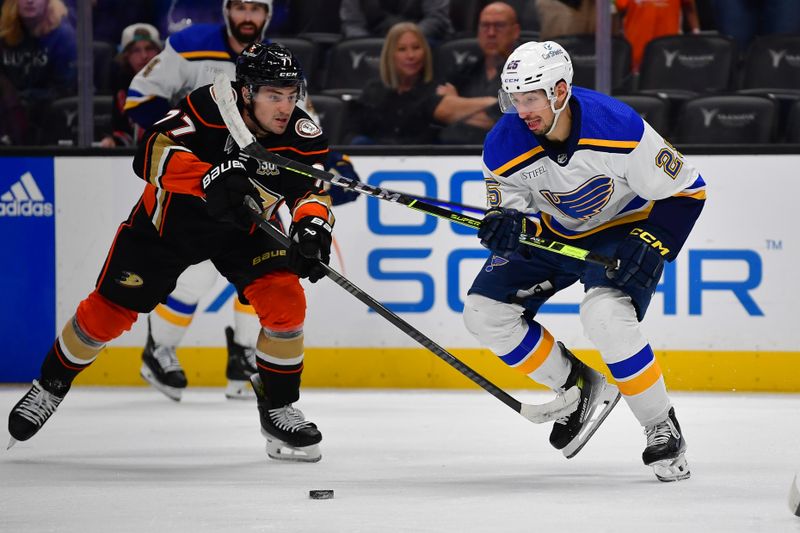 Apr 7, 2024; Anaheim, California, USA; Anaheim Ducks right wing Frank Vatrano (77) plays for the puck against St. Louis Blues center Jordan Kyrou (25) during the third period at Honda Center. Mandatory Credit: Gary A. Vasquez-USA TODAY Sports