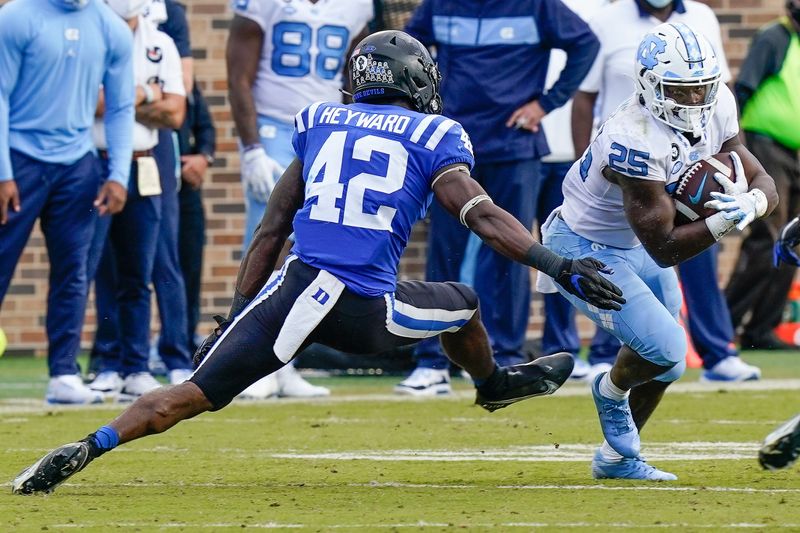 Nov 7, 2020; Durham, North Carolina, USA; North Carolina Tar Heels running back Javonte Williams (25) runs away from Duke Blue Devils linebacker Shaka Heyward (42) during the second half at Wallace Wade Stadium. Mandatory Credit: Jim Dedmon-USA TODAY Sports