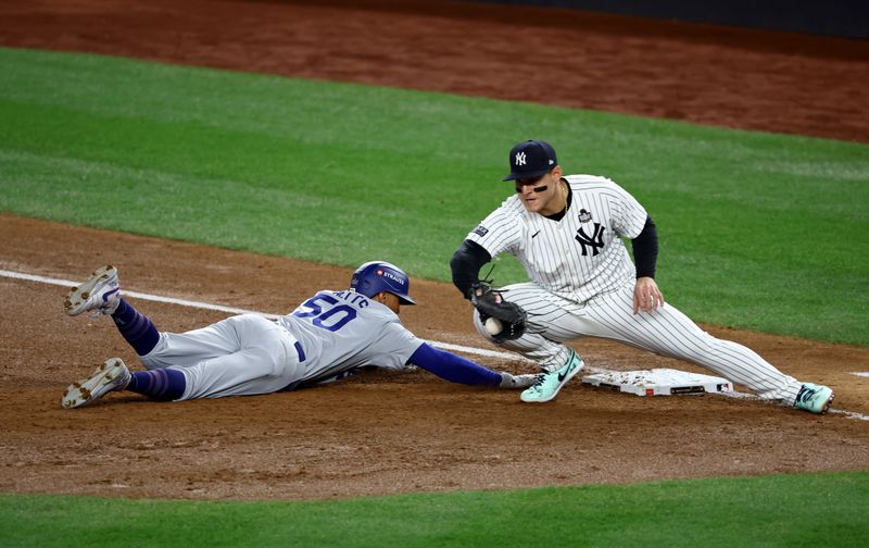 Oct 28, 2024; New York, New York, USA; Los Angeles Dodgers shortstop Mookie Betts (50) slides back safely under the tag of New York Yankees first baseman Anthony Rizzo (48) during the third inning in game three of the 2024 MLB World Series at Yankee Stadium. Mandatory Credit: Vincent Carchietta-Imagn Images