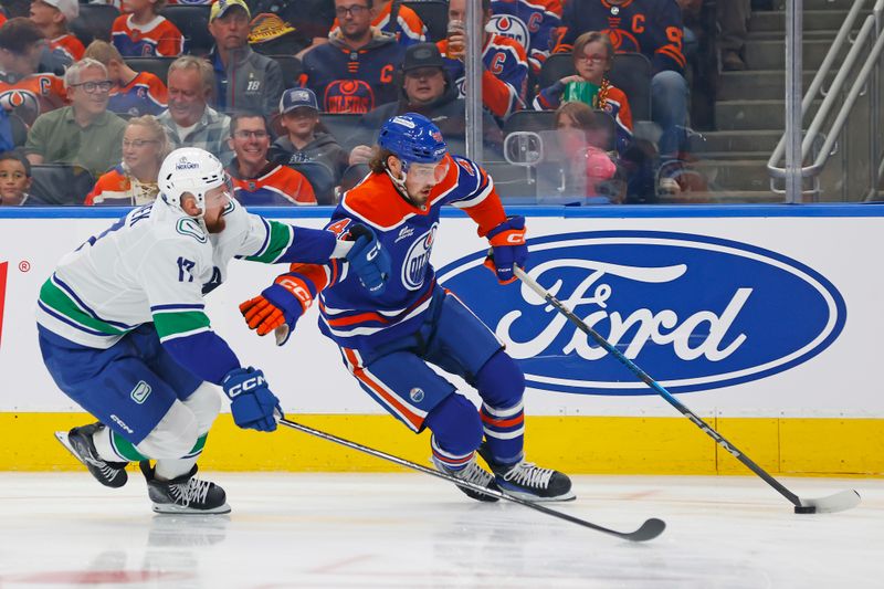 Oct 11, 2025; Edmonton, Alberta, CAN; Vancouver Canucks defensemen Filip Hornek (17) tries to knock the puck away from Edmonton Oilers forward Noah Philp (48) during the first period at Rogers Place. Mandatory Credit: Perry Nelson-Imagn Images