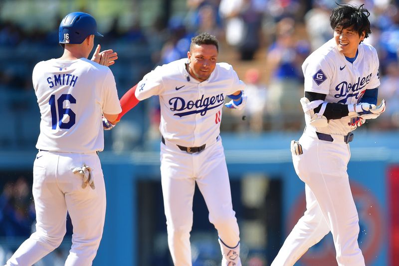 May 19, 2024; Los Angeles, California, USA; Los Angeles Dodgers shortstop Miguel Rojas (11) and catcher Will Smith (16) celebrate after designated hitter Shohei Ohtani (17) hits a walk off RBI single during the tenth inning against the Cincinnati Reds at Dodger Stadium. Mandatory Credit: Gary A. Vasquez-USA TODAY Sports