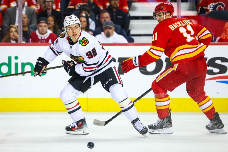 Oct 15, 2024; Calgary, Alberta, CAN; Chicago Blackhawks center Connor Bedard (98) and Calgary Flames center Mikael Backlund (11) battles for the puck during the first period at Scotiabank Saddledome. Mandatory Credit: Sergei Belski-Imagn Images