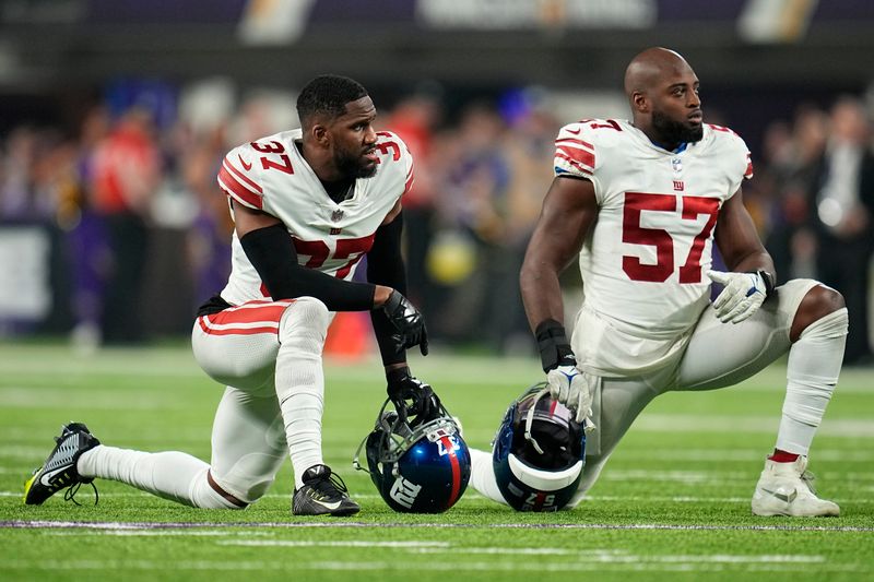 New York Giants cornerback Fabian Moreau (37), left, and linebacker Jarrad Davis (57) take a knee during second half of an NFL wild-card football game against the Minnesota Vikings, Sunday, Jan. 15, 2023, in Minneapolis. (AP Photo/Abbie Parr)