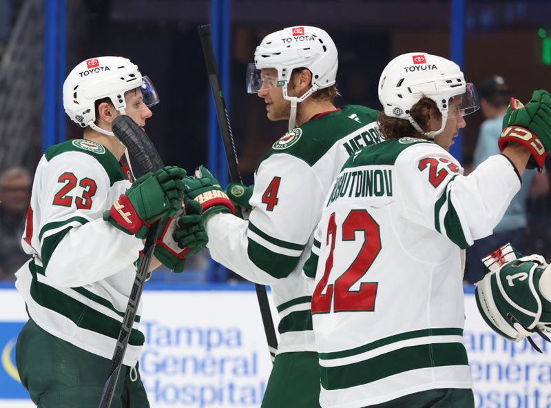 Oct 24, 2024; Tampa, Florida, USA; Minnesota Wild center Marco Rossi (23), defenseman Jon Merrill (4)anld center Marat Khusnutdinov (22) celebrate after they beat the Tampa Bay Lightning at Amalie Arena. Mandatory Credit: Kim Klement Neitzel-Imagn Images