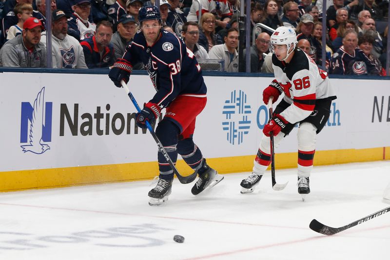 Oct 13, 2025; Columbus, Ohio, USA; Columbus Blue Jackets center Boone Jenner (38) passes the puck as New Jersey Devils center Jack Hughes (86) trails the play during the first period at Nationwide Arena. Mandatory Credit: Russell LaBounty-Imagn Images