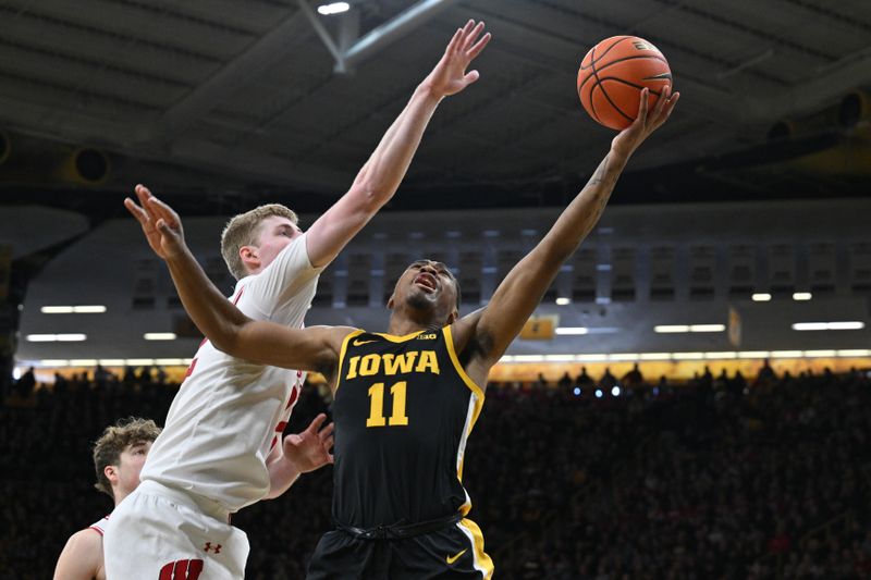 Feb 17, 2024; Iowa City, Iowa, USA; Iowa Hawkeyes guard Tony Perkins (11) shoots the ball as Wisconsin Badgers forward Steven Crowl (22) defends during the second half at Carver-Hawkeye Arena. Mandatory Credit: Jeffrey Becker-USA TODAY Sports