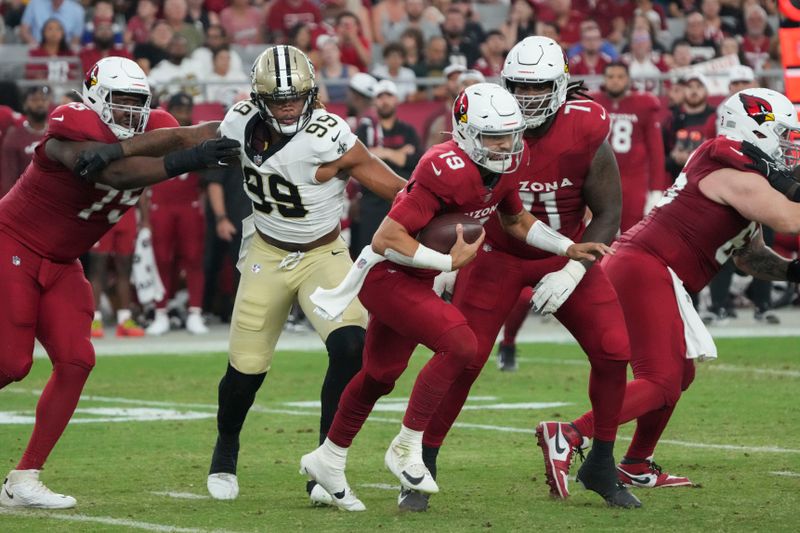 Arizona Cardinals quarterback Desmond Ridder (19) scrambles from New Orleans Saints defensive end Chase Young (99) in the first half of a preseason NFL football game, Saturday, Aug. 10, 2024, in Glendale, Ariz. (AP Photo/Rick Scuteri)