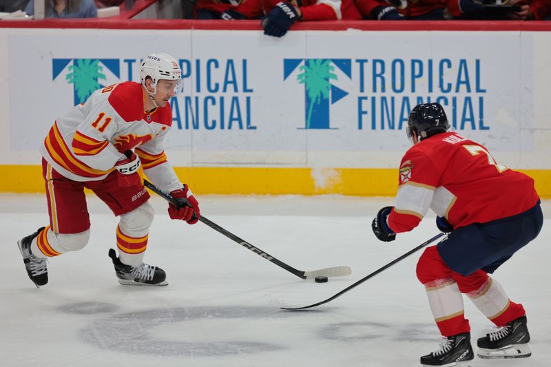 Mar 1, 2025; Sunrise, Florida, USA; Calgary Flames center Mikael Backlund (11) moves the puck as Florida Panthers defenseman Dmitry Kulikov (7) defends during the third period at Amerant Bank Arena. Mandatory Credit: Sam Navarro-Imagn Images