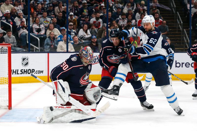 Nov 1, 2024; Columbus, Ohio, USA; Columbus Blue Jackets defenseman Jack Johnson (3) ties up Winnipeg Jets right wing Nino Niederreiter (62) as goalie Elvis Merzlikins (90) makes a save during the third period at Nationwide Arena. Mandatory Credit: Russell LaBounty-Imagn Images