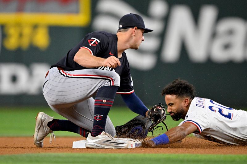 Sep 24, 2025; Arlington, Texas, USA; Texas Rangers shortstop Ezequiel Duran (20) slides under the tag of Minnesota Twins shortstop Brooks Lee (2) during the seventh inning at Globe Life Field. Mandatory Credit: Jerome Miron-Imagn Images
