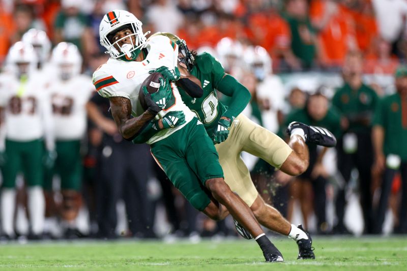 Sep 21, 2024; Tampa, Florida, USA; Miami Hurricanes wide receiver Jacolby George (3) is tackled by South Florida Bulls cornerback Brent Austin (20) in the first quarter at Raymond James Stadium. Mandatory Credit: Nathan Ray Seebeck-Imagn Images