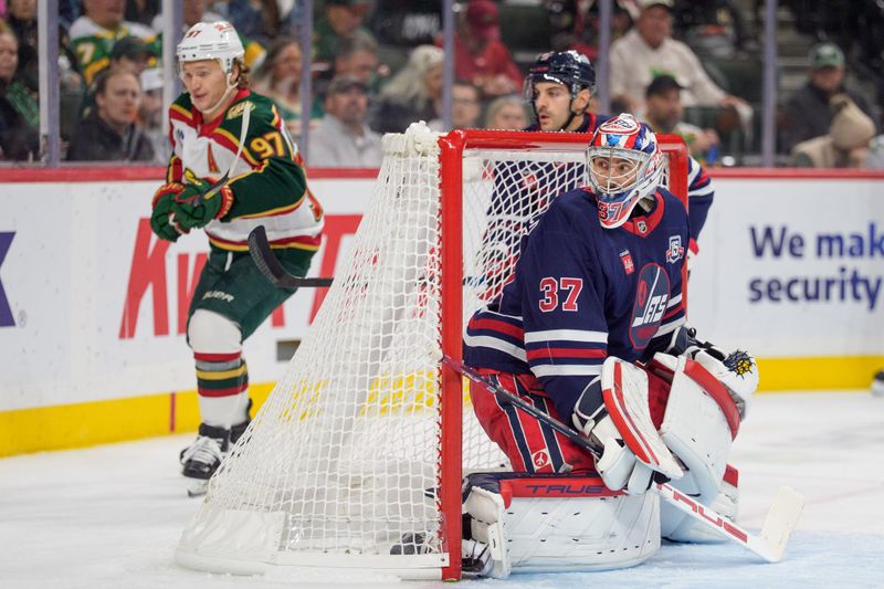 Oct 28, 2025; Saint Paul, Minnesota, USA; Winnipeg Jets goaltender Connor Hellebuyck (37) watches the puck in the corner as Minnesota Wild left wing Kirill Kaprizov (97) awaits a pass behind the net in the second period at Grand Casino Arena. Mandatory Credit: Matt Blewett-Imagn Images