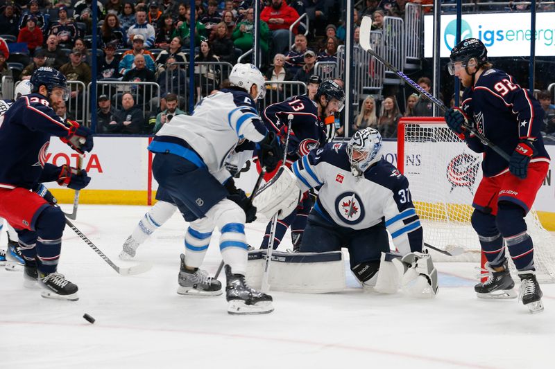 Mar 17, 2024; Columbus, Ohio, USA; Winnipeg Jets goalie Connor Hellebuyck (37) makes a pad save as Columbus Blue Jackets left wing Alexander Nylander (92) looks for a rebound during the second period at Nationwide Arena. Mandatory Credit: Russell LaBounty-USA TODAY Sports