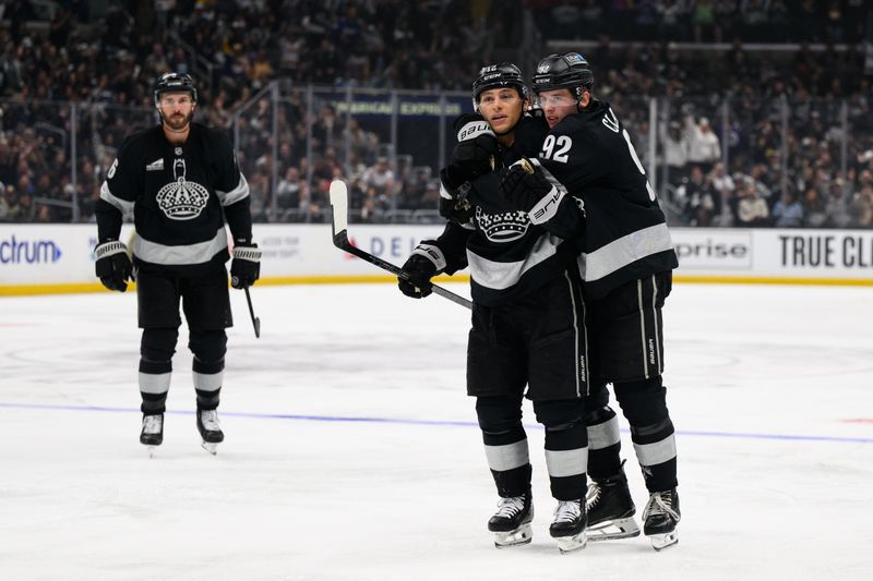 Oct 18, 2025; Los Angeles, California, USA; Los Angeles Kings left wing Trevor Moore (12), center, is greeted by defenseman Brandt Clarke (92) after scoring during the second period against the Carolina Hurricanes at Crypto.com Arena. Mandatory Credit: William Liang-Imagn Images