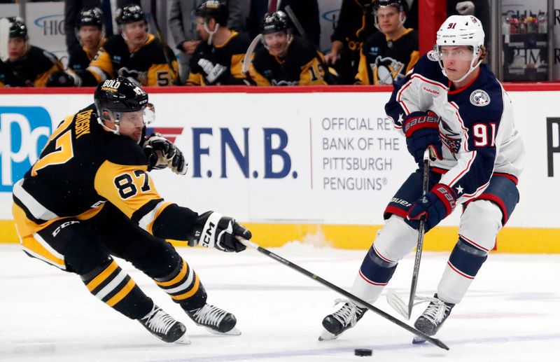 Oct 4, 2024; Pittsburgh, Pennsylvania, USA;  Columbus Blue Jackets center Kent Johnson (91) moves the puck against Pittsburgh Penguins center Sidney Crosby (87) during the first period at PPG Paints Arena. Mandatory Credit: Charles LeClaire-Imagn Images