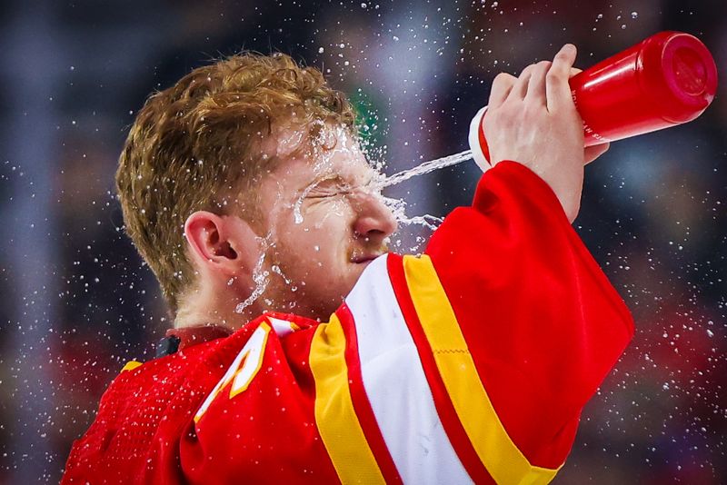 Mar 24, 2024; Calgary, Alberta, CAN; Calgary Flames goaltender Dustin Wolf (32) sprays water in his face during the first period against the Buffalo Sabres at Scotiabank Saddledome. Mandatory Credit: Sergei Belski-USA TODAY Sports