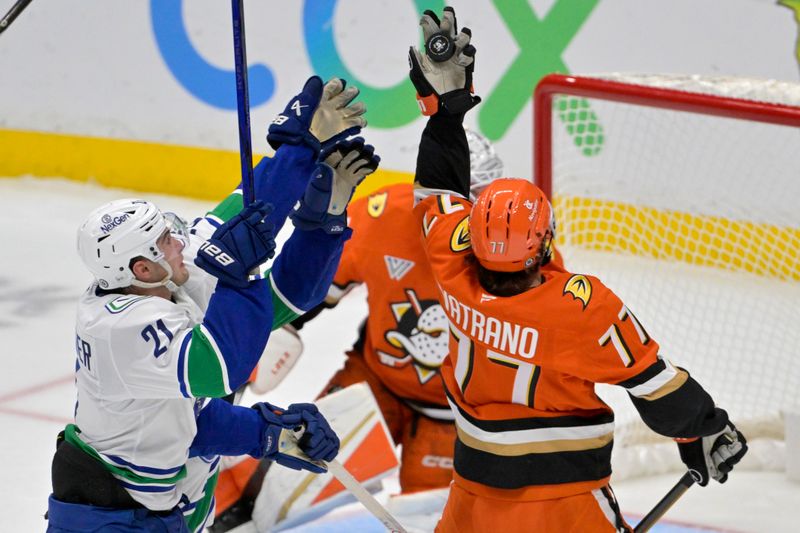 Nov 5, 2024; Anaheim, California, USA; Anaheim Ducks right wing Frank Vatrano (77) deflects a shot on goal in front of Vancouver Canucks left wing Nils Hoglander (21) in the second period at Honda Center. Mandatory Credit: Jayne Kamin-Oncea-Imagn Images