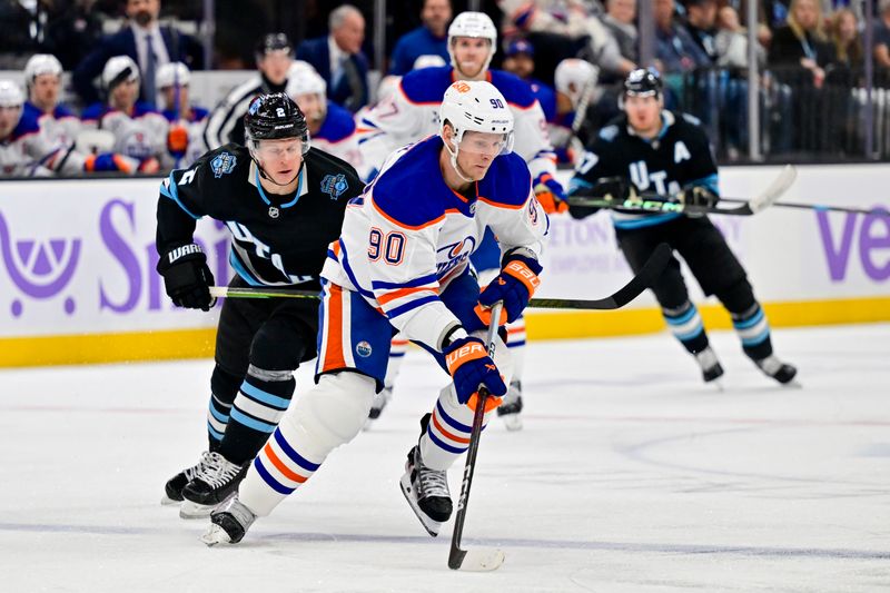 Nov 29, 2024; Salt Lake City, Utah, USA; Edmonton Oilers right wing Corey Perry (90) moves the puck past Utah Hockey Club defenseman Olli Maatta (2) during the third period at the Delta Center. Mandatory Credit: Christopher Creveling-Imagn Images