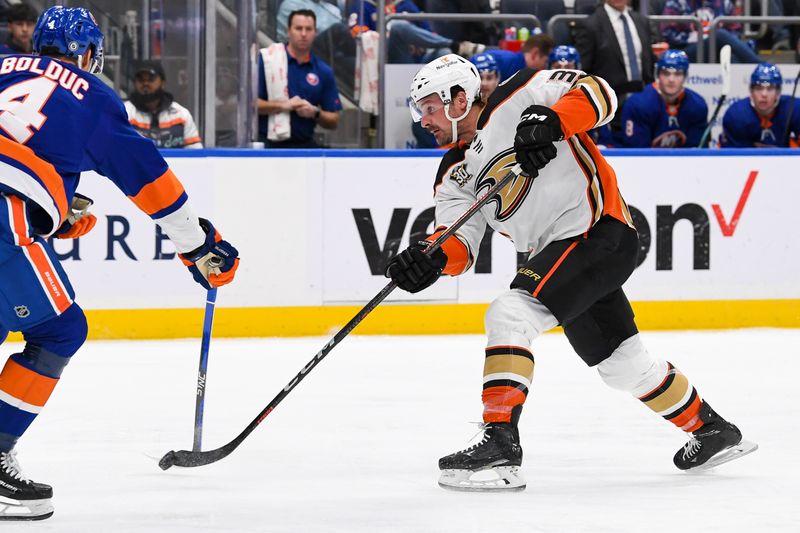 Dec 13, 2023; Elmont, New York, USA; Anaheim Ducks center Sam Carrick (39) shoots the puck defended by New York Islanders defenseman Samuel Bolduc (4) during the third period at UBS Arena. Mandatory Credit: Dennis Schneidler-USA TODAY Sports