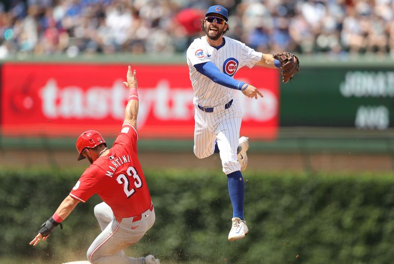 May 31, 2024; Chicago, Illinois, USA; Cincinnati Reds outfielder Nick Martini (23) slides as Chicago Cubs shortstop Dansby Swanson (7) throws the ball to first base for a double play during the fourth inning at Wrigley Field. Mandatory Credit: Melissa Tamez-USA TODAY Sports