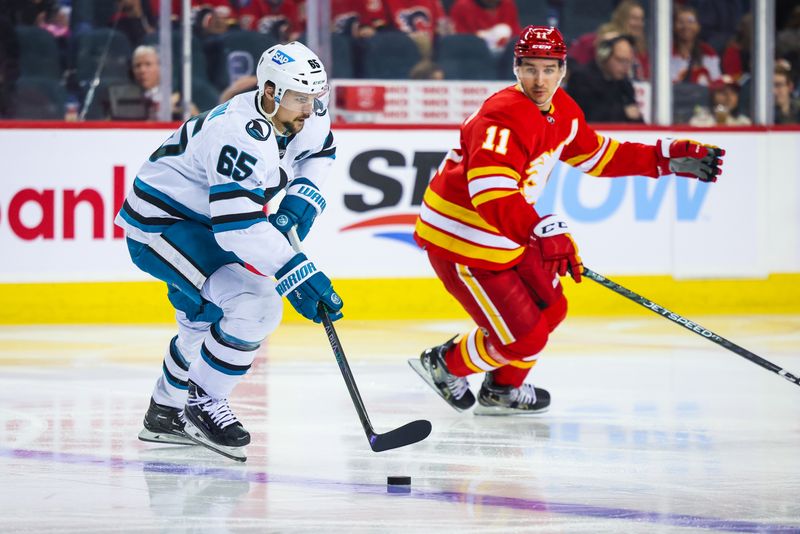 Apr 12, 2023; Calgary, Alberta, CAN; San Jose Sharks defenseman Erik Karlsson (65) controls the puck in front of Calgary Flames center Mikael Backlund (11) during the second period at Scotiabank Saddledome. Mandatory Credit: Sergei Belski-USA TODAY Sports