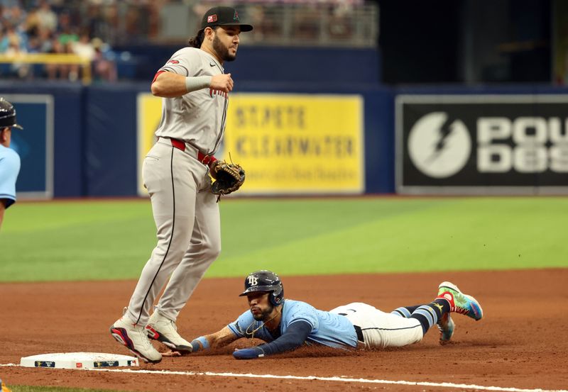 Aug 18, 2024; St. Petersburg, Florida, USA; Tampa Bay Rays second baseman Jose Caballero (7) slides as he steals third base as Arizona Diamondbacks third base Eugenio Suarez (28) looks on during the fifth inning at Tropicana Field. Mandatory Credit: Kim Klement Neitzel-USA TODAY Sports