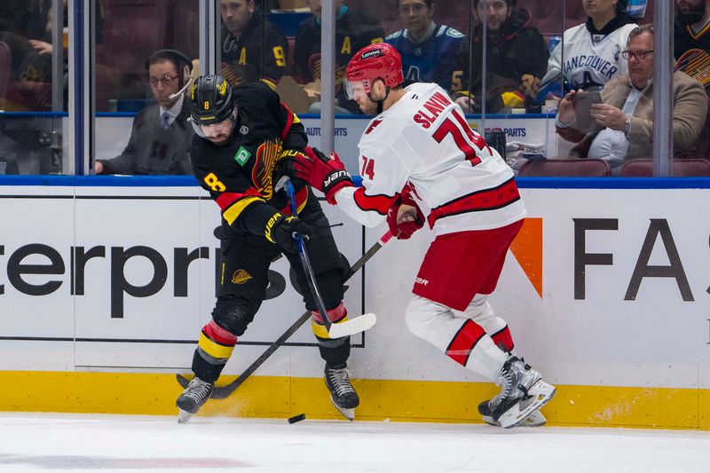 Oct 28, 2024; Vancouver, British Columbia, CAN; Carolina Hurricanes defenseman Jaccob Slavin (74) stick checks Vancouver Canucks forward Conor Garland (8) during the first period at Rogers Arena. Mandatory Credit: Bob Frid-Imagn Images