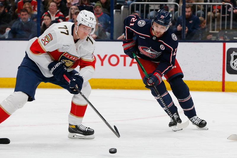 Mar 20, 2025; Columbus, Ohio, USA; Florida Panthers defenseman Niko Mikkola (77) clears a loose puck as Columbus Blue Jackets left wing James van Riemsdyk (21) look for the rebound during the second period at Nationwide Arena. Mandatory Credit: Russell LaBounty-Imagn Images