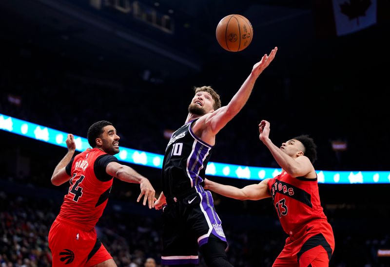 TORONTO, ON - MARCH 20: Domantas Sabonis #10 of the Sacramento Kings battles for a rebound against Jordan Nwora #13 and Jontay Porter #34 of the Toronto Raptors during the first half at the Scotiabank Arena on March 20, 2024 in Toronto, Ontario, Canada. NOTE TO USER: User expressly acknowledges and agrees that, by downloading and/or using this Photograph, user is consenting to the terms and conditions of the Getty Images License Agreement. (Photo by Mark Blinch/Getty Images)