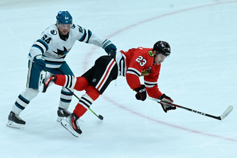 Jan 16, 2024; Chicago, Illinois, USA; Chicago Blackhawks center Philipp Kurashev (23) and San Jose Sharks right wing Mitchell Russell (64) chase the puck during the second period at United Center. Mandatory Credit: Matt Marton-USA TODAY Sports