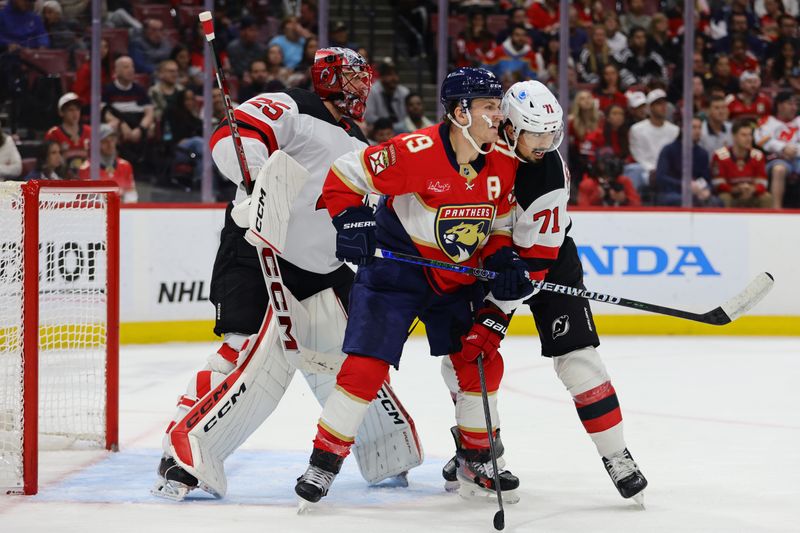 Nov 12, 2024; Sunrise, Florida, USA; New Jersey Devils defenseman Jonas Siegenthaler (71) and goaltender Jacob Markstrom (25) defend against Florida Panthers left wing Matthew Tkachuk (19) during the second period at Amerant Bank Arena. Mandatory Credit: Sam Navarro-Imagn Images