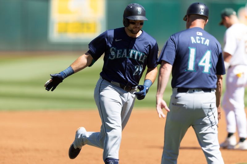 Sep 5, 2024; Oakland, California, USA; Seattle Mariners catcher Cal Raleigh (29) gets a congratulatory handshake from third base coach Manny Acta (14) after hitting a two-run home run against the Oakland Athletics during the first inning at Oakland-Alameda County Coliseum. Mandatory Credit: D. Ross Cameron-Imagn Images