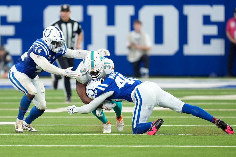 Indianapolis Colts linebacker Zaire Franklin (44) and cornerback Jaylon Jones (40) take down Miami Dolphins running back Raheem Mostert (31) during the first half of an NFL football game, Sunday, Oct. 20, 2024 in Indianapolis. (AP Photo/Michael Conroy)