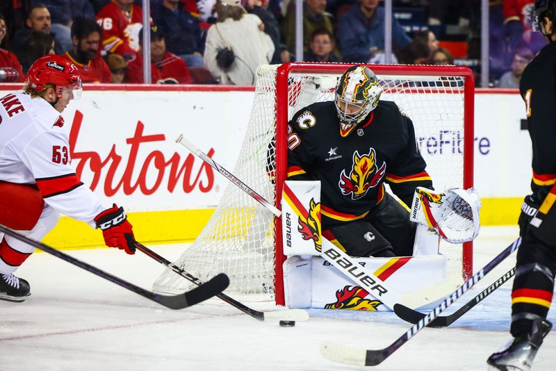 Oct 24, 2024; Calgary, Alberta, CAN; Calgary Flames goaltender Dan Vladar (80) guards his net against Carolina Hurricanes right wing Jackson Blake (53) during the first period at Scotiabank Saddledome. Mandatory Credit: Sergei Belski-Imagn Images